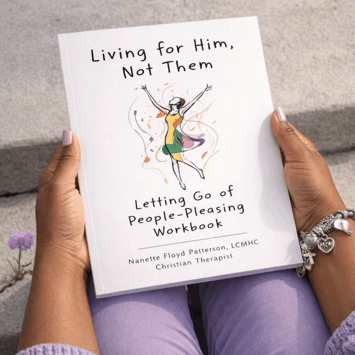 Christian self-help workbook titled “Living for Him, Not Them: Letting Go of People-Pleasing Workbook” by therapist Nanette Floyd Patterson, shown in a photorealistic top-down lifestyle scene. An African American woman sits on concrete steps holding the 8.5 x 11 soft paperback book, with lavender nails, purple clothing, and a silver charm bracelet. A purple dandelion growing from a crack symbolizes healing, faith, emotional wellness, and overcoming people-pleasing.